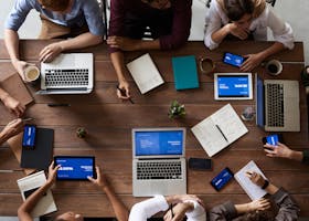 Overhead view of a diverse team in a business meeting using laptops and tablets.